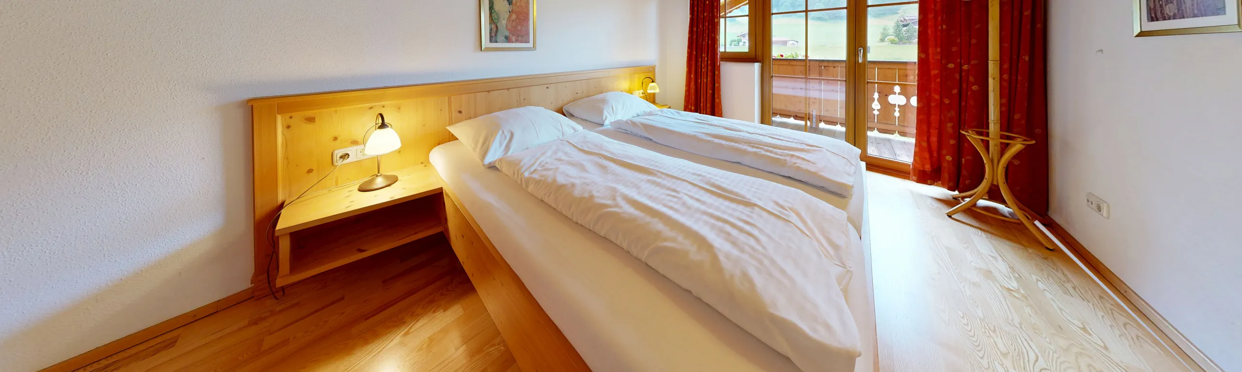 Panoramaansicht eines Schlafzimmers mit Holzbetten und Balkon