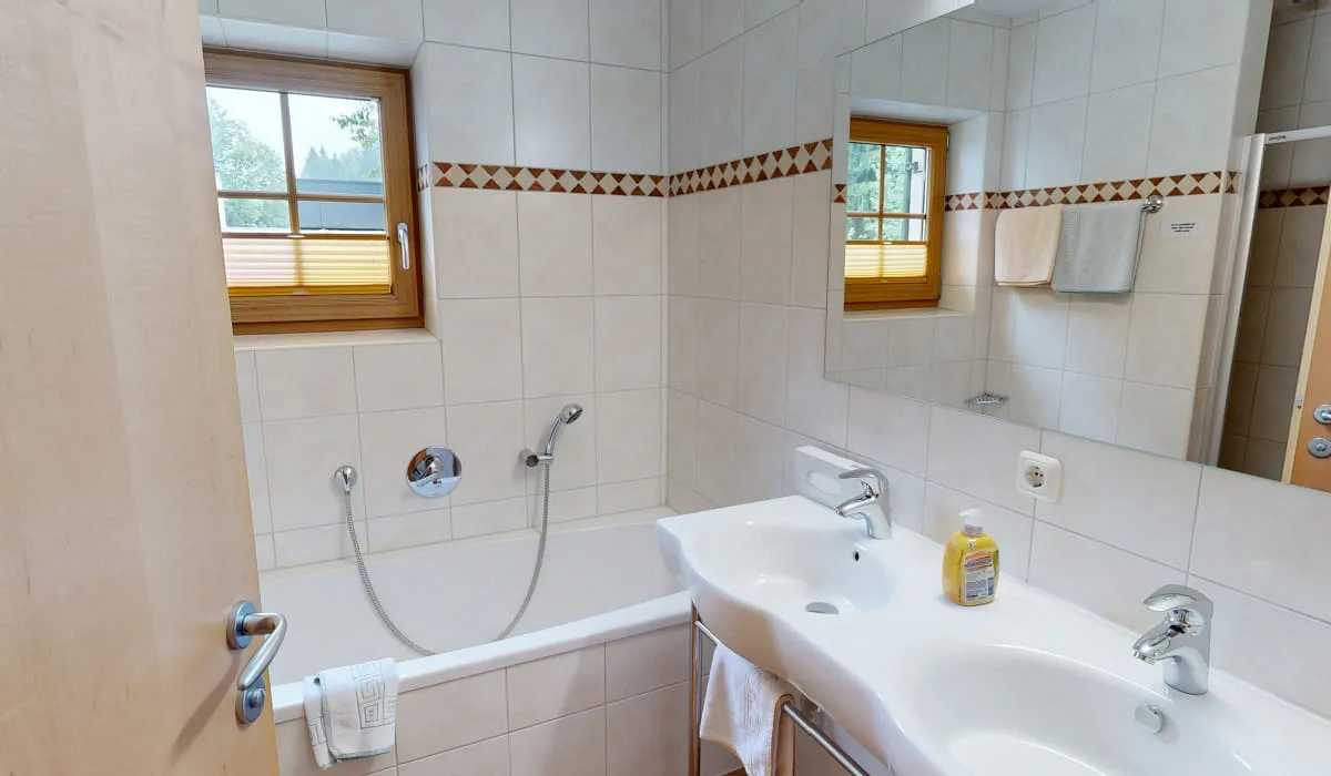Helles Badezimmer mit Dusche, Badewanne, Waschbecken und Fenster.