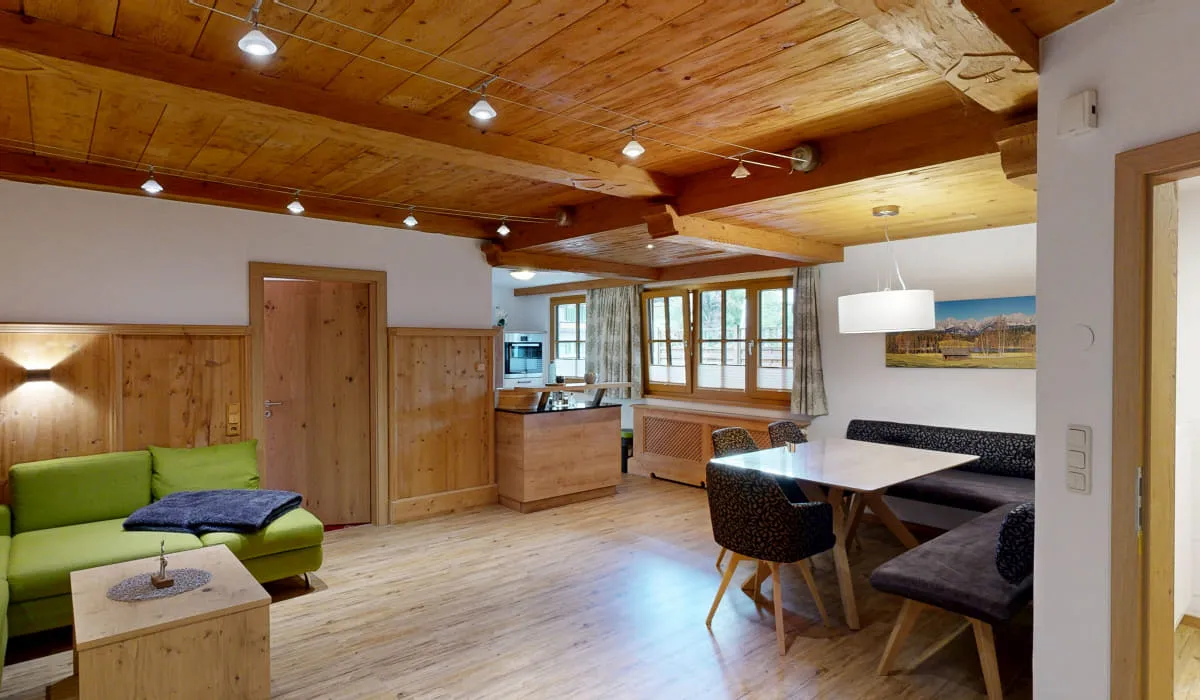 einladender Wohnbereich mit grüner Couch und Essbereich aus Holz