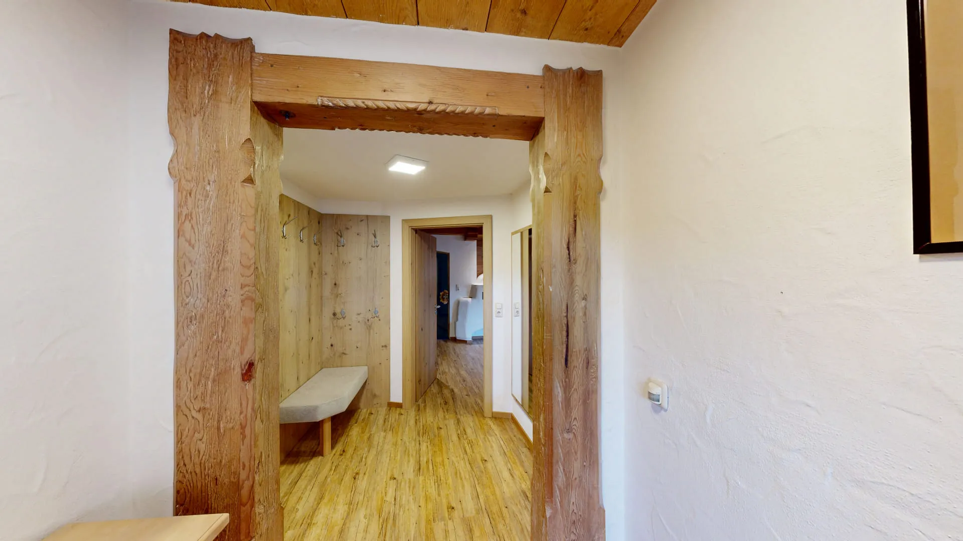 Blick durch einen Holzrahmen in einen Flur mit Holzboden und Wänden