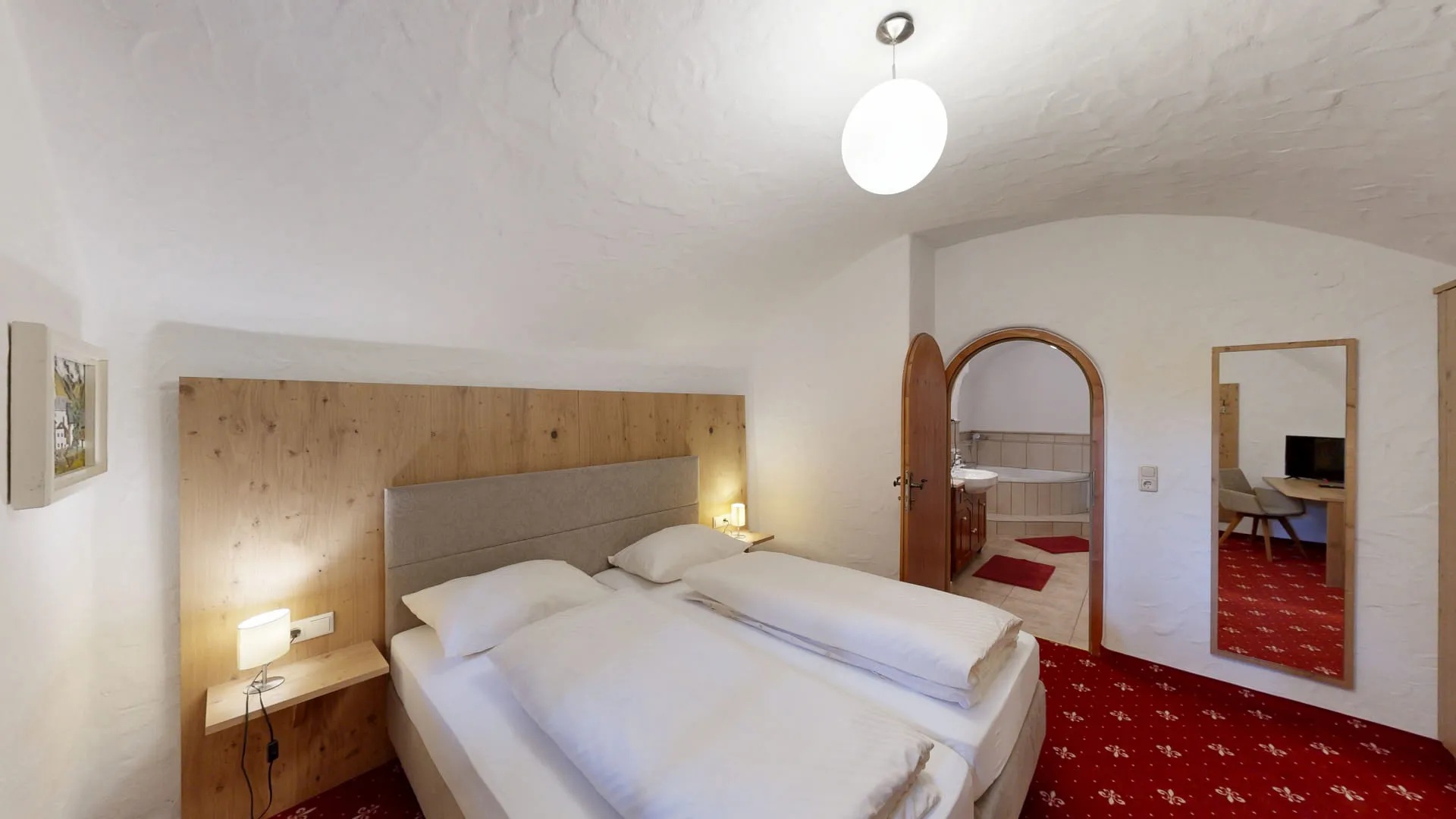 Blick in ein gemütliches Schlafzimmer mit zwei Betten und einem Spiegel